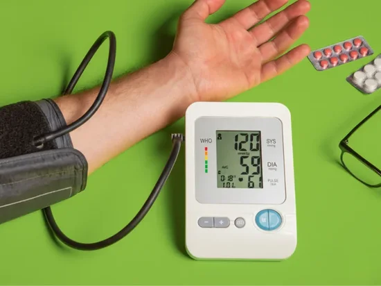 Person using digital blood pressure monitor at home showing healthy reading of 120 over 59 mmHg.