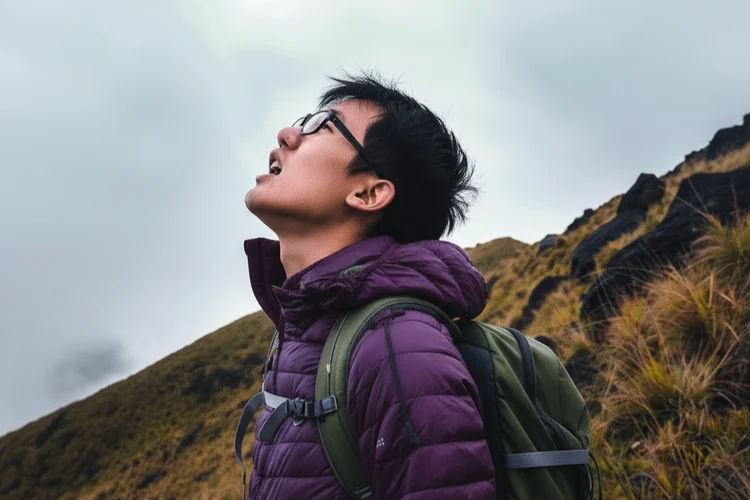Climber breathing heavily on mountain slope showing fatigue and mild side effects at high altitude.