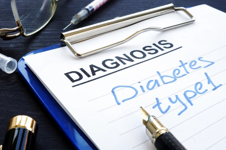 Clipboard with medical form marked type 1 diabetes diagnosis alongside syringe, pen, and eyeglasses.