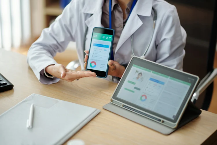 Doctor showing digital health screening results on phone and tablet during a longevity consultation.