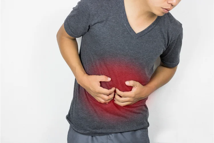 Man clutching abdomen in discomfort showing possible digestive symptoms of gut microbiome imbalance.
