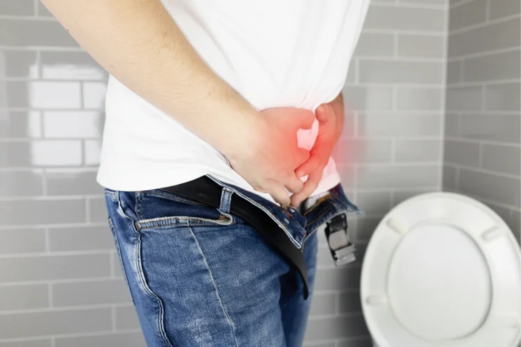 Man holding groin in pain showing common symptoms of chancroid such as painful genital ulcers.