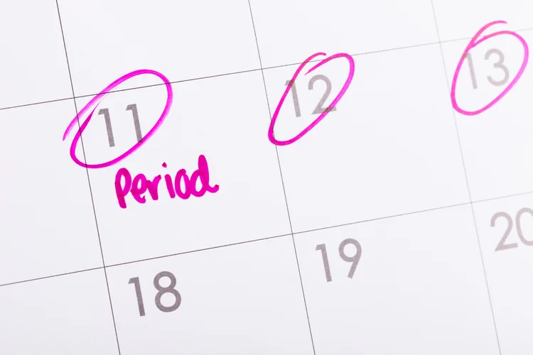 Marked calendar showing menstrual period dates for planning premarital health screening appointment.