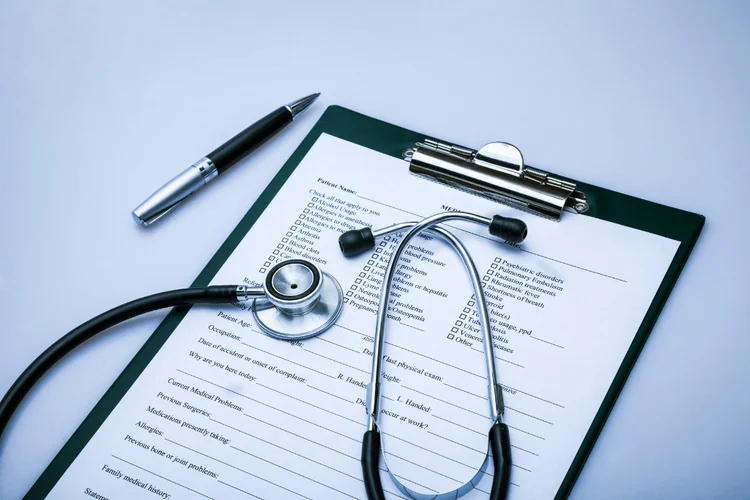 Medical questionnaire and stethoscope on desk used for comprehensive health screening assessments.