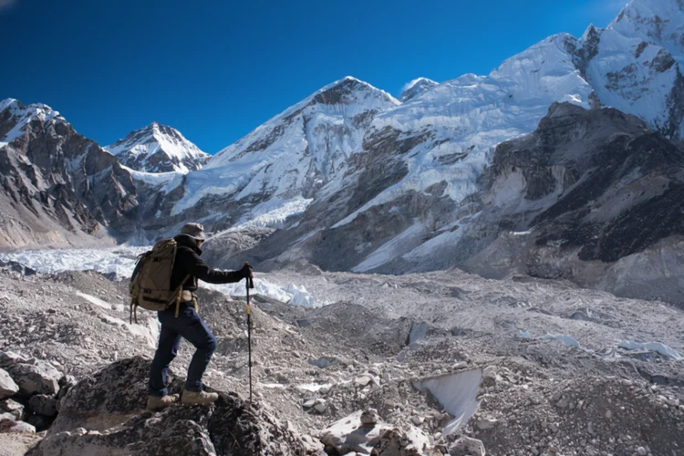 Trekker pausing to rest in snowy mountains illustrating gradual ascent to prevent altitude sickness.