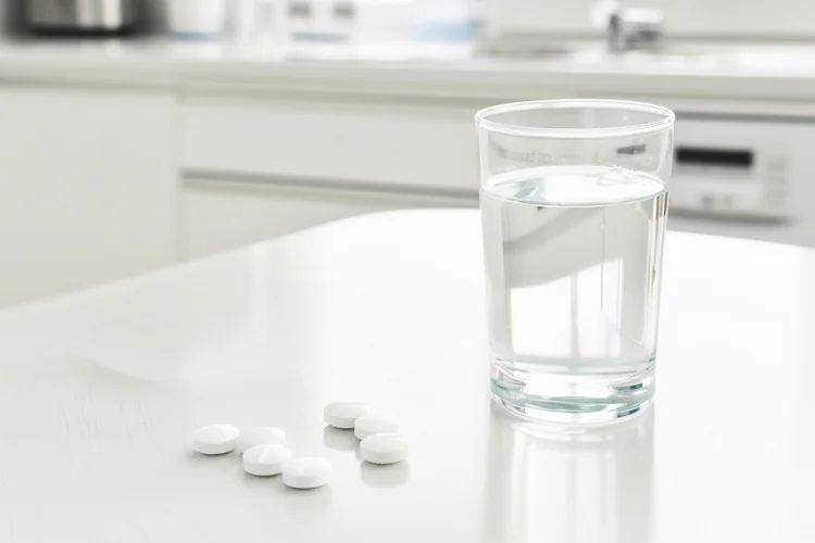 White malaria tablets with a glass of water showing proper timing for taking malaria medication.