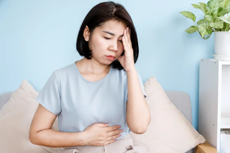 Woman feeling dizzy and unwell at home showing possible symptoms of high blood pressure hypertension.