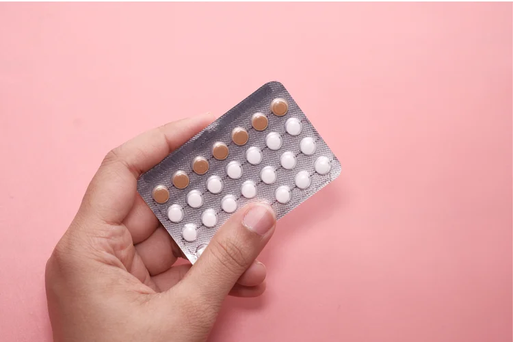 Woman holding birth control pill pack to prevent pregnancy and regulate menstrual cycle in Singapore.