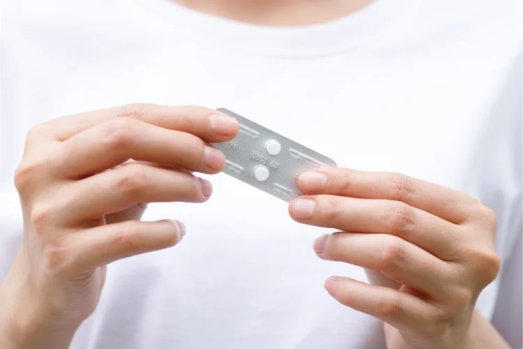 Woman holding emergency contraceptive pill strip showing how it is taken after unprotected sex.