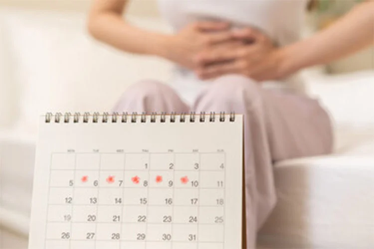Woman holding stomach with menstrual calendar in front, representing hormonal contraceptive function.
